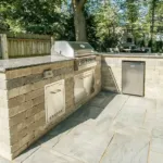 Backyard outdoor kitchen and hardscape installation with stone countertops and built-in appliances