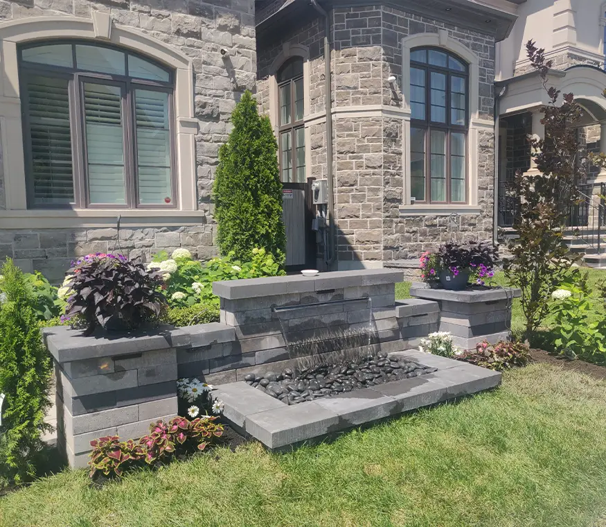 Close-up of front yard water feature with stonework and surrounding plants