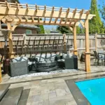 Custom pergola and deck built by professional landscape and hardscape contractors in a backyard setting