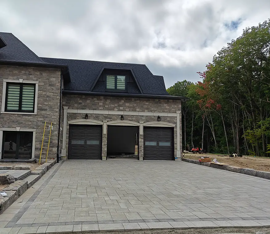 Front yard interlock driveway and stone edging under construction