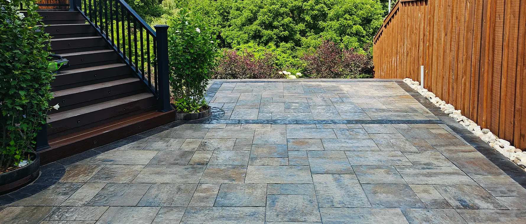 Large-format interlock patio installation in Kitchener Ontario beside custom deck stairs