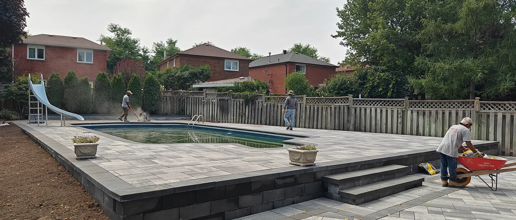 Large-format interlock patio surrounding backyard pool in Brampton Ontario during installation