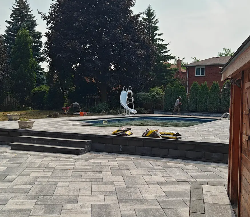 Poolside interlock paver installation in Brampton Ontario with raised retaining wall edge