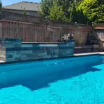 Poolside water feature and retaining wall built by experienced pool and hardscape contractors in Brampton Ontario