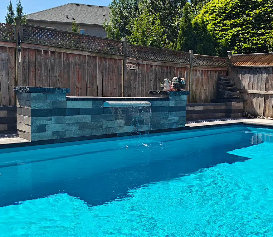 Poolside water feature and retaining wall built by experienced pool and hardscape contractors in Brampton Ontario