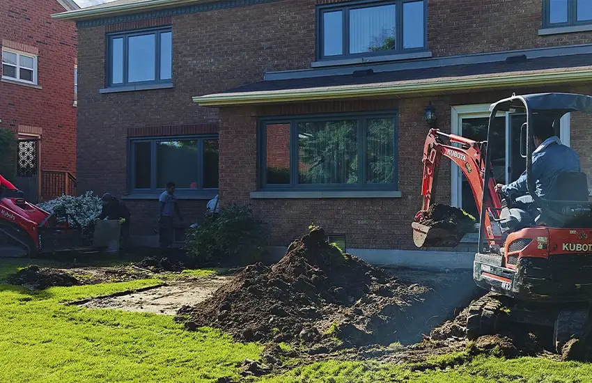 Professional landscaping and hardscaping installation with excavation equipment at a residential property in the GTA