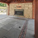 Stone fireplace feature integrated into hardscape patio design in Aurora Ontario by outdoor contractors