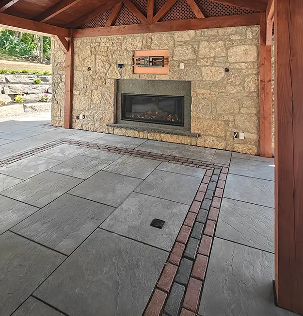 Stone fireplace feature integrated into hardscape patio design in Aurora Ontario by outdoor contractors