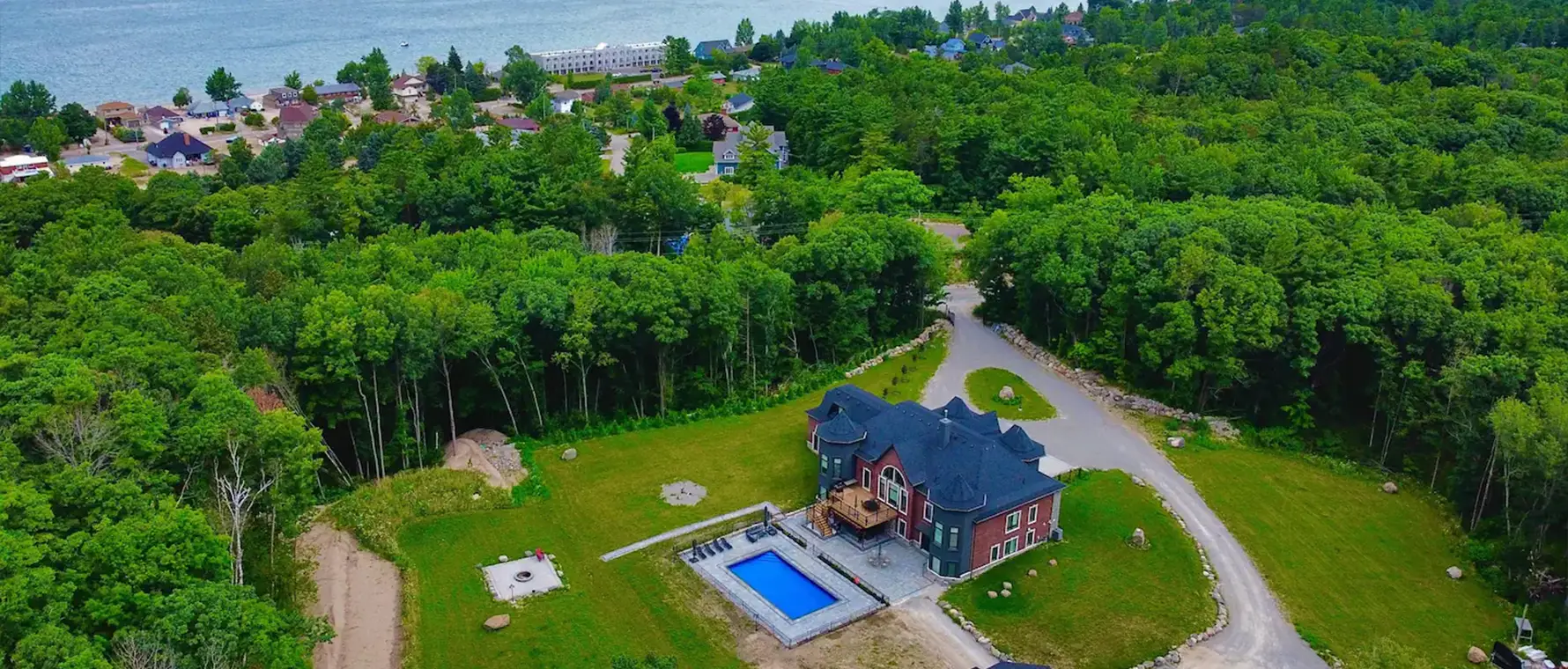 Wide aerial view of backyard interlock pool area and surrounding landscape