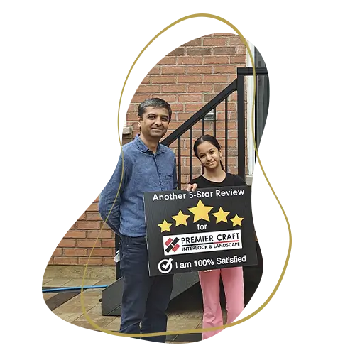 Happy homeowners holding a five-star review sign following a residential landscaping and interlock project