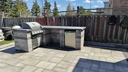 Stone BBQ grill integrated into patio by interlocking contractor